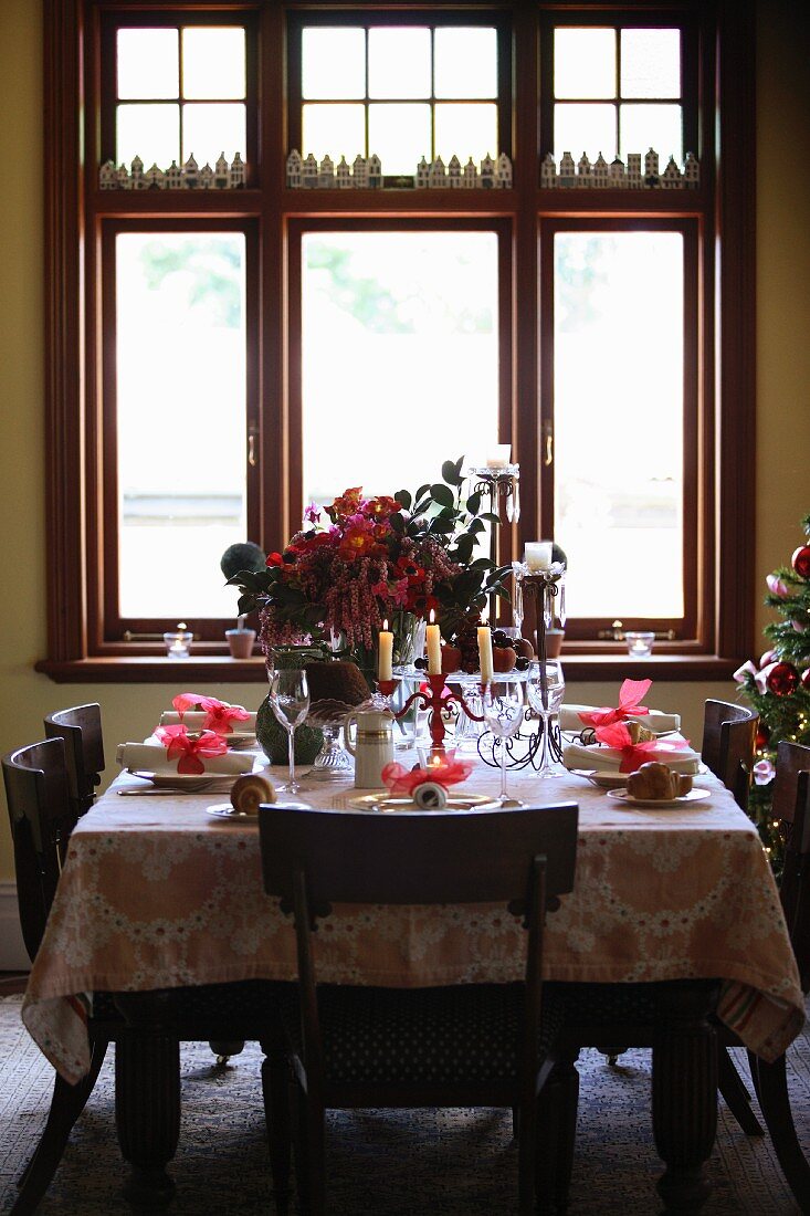 Gedeckter Weihnachtstisch vor großem Fenster