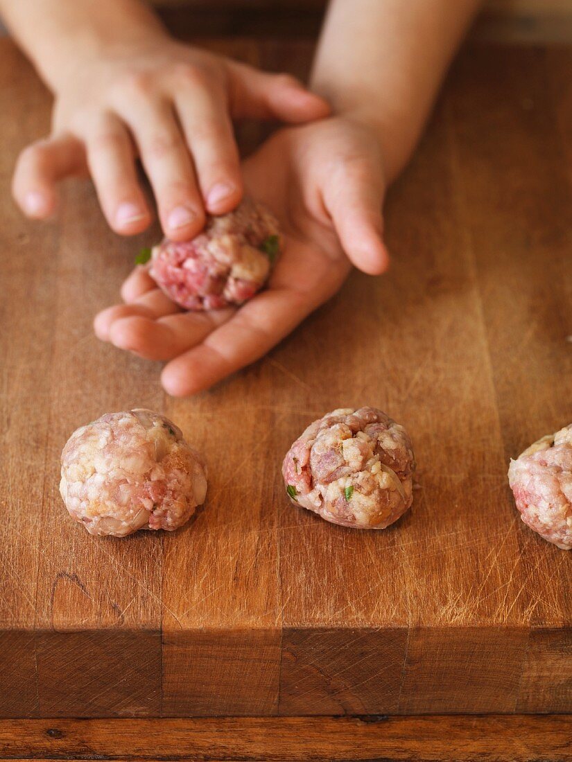 A child's hands shaping meatballs