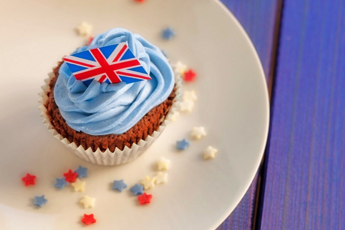 A chocolate cupcake topped with blue buttercream and a Union Jack