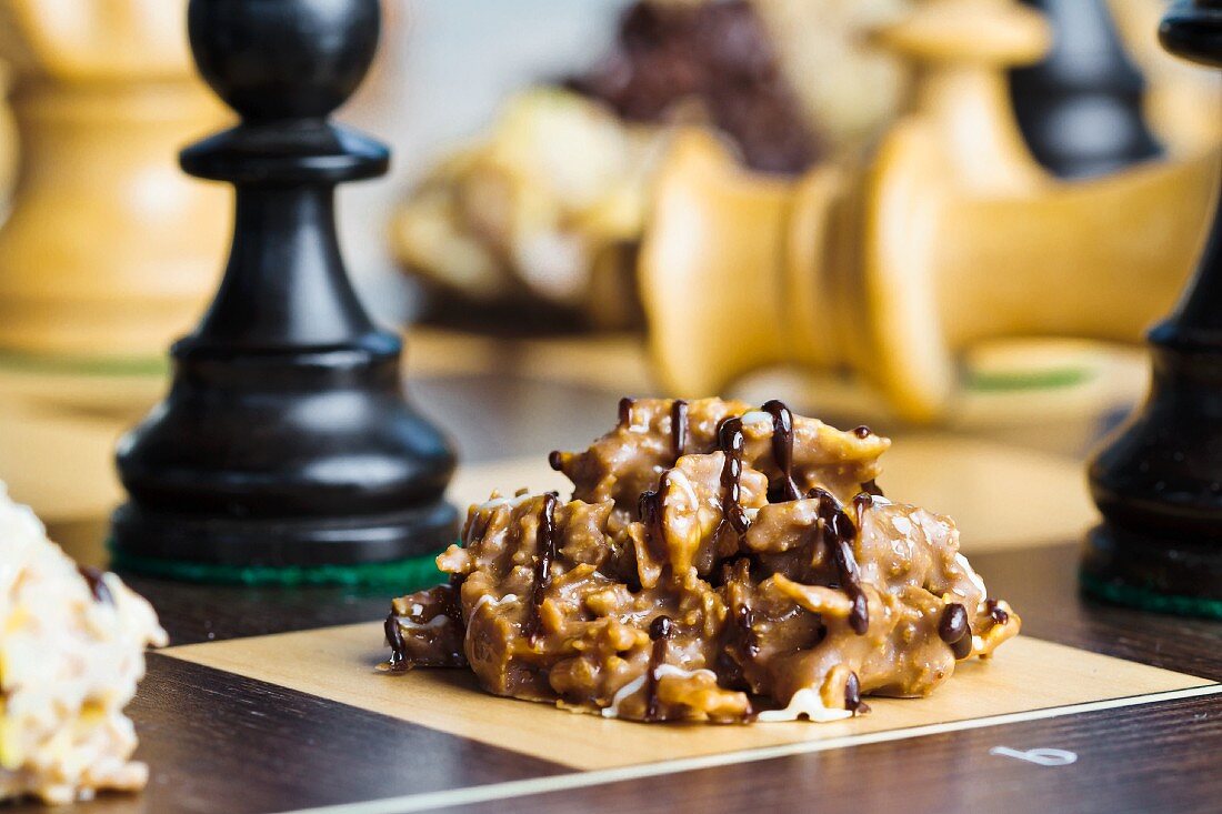 Nut brittle drizzled with chocolate on a chessboard