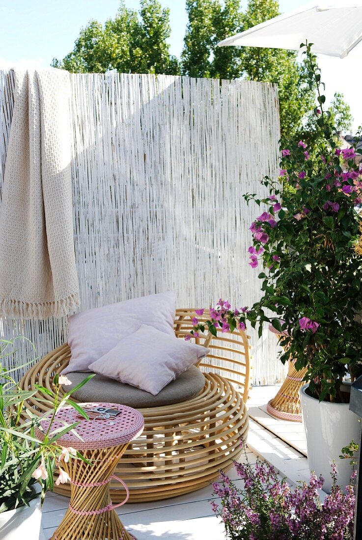 Wicker lounger, stool and bamboo screen on terrace