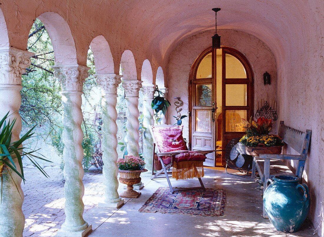 Antique and vases in a pink arcade with arched double doors