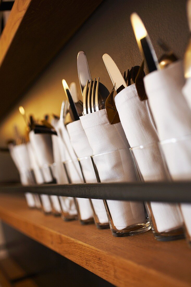Sets of cutlery on a wooden shelf in a guesthouse