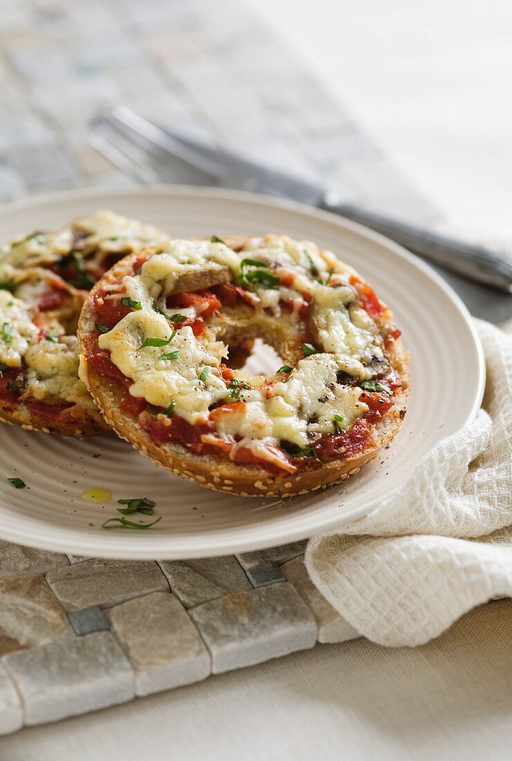 A bagel topped with mushrooms, tomatoes and cheese