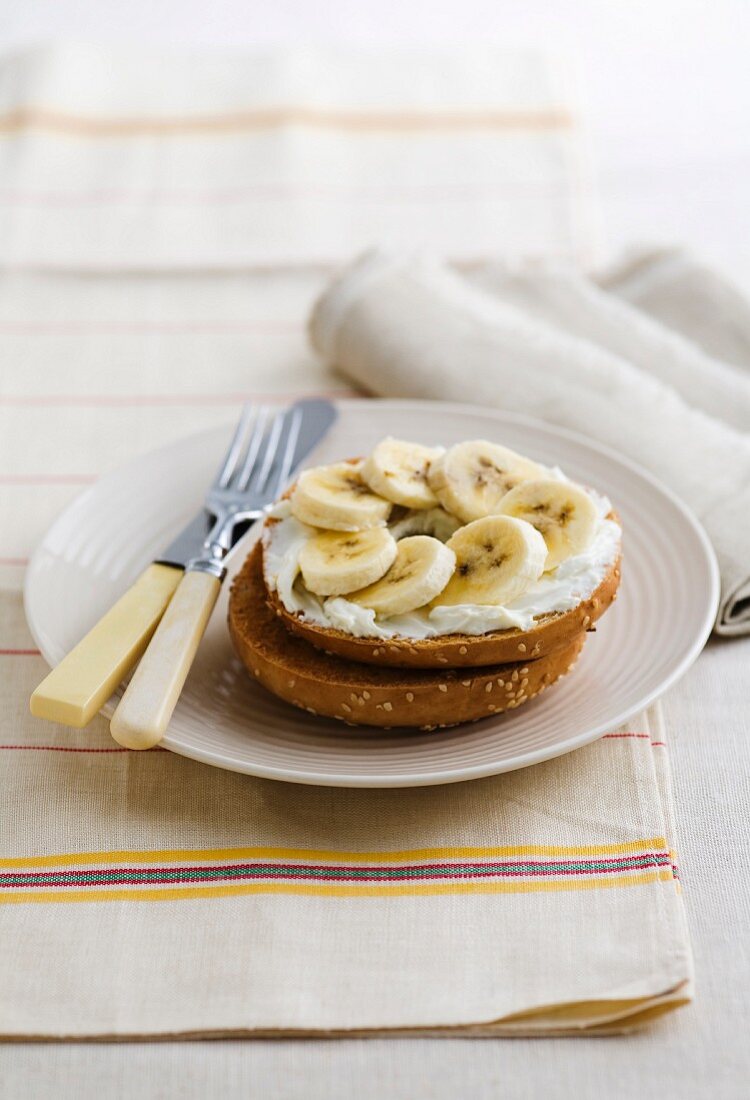 A bagel topped with cream cheese and banana