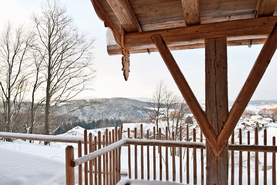 Detail of wooden fence, wooden support and rustic roof structure in snowy mountain landscape