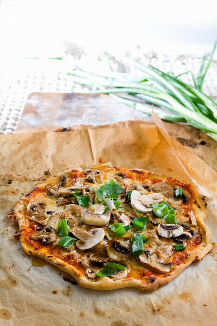A mushroom pizza on a piece of baking paper