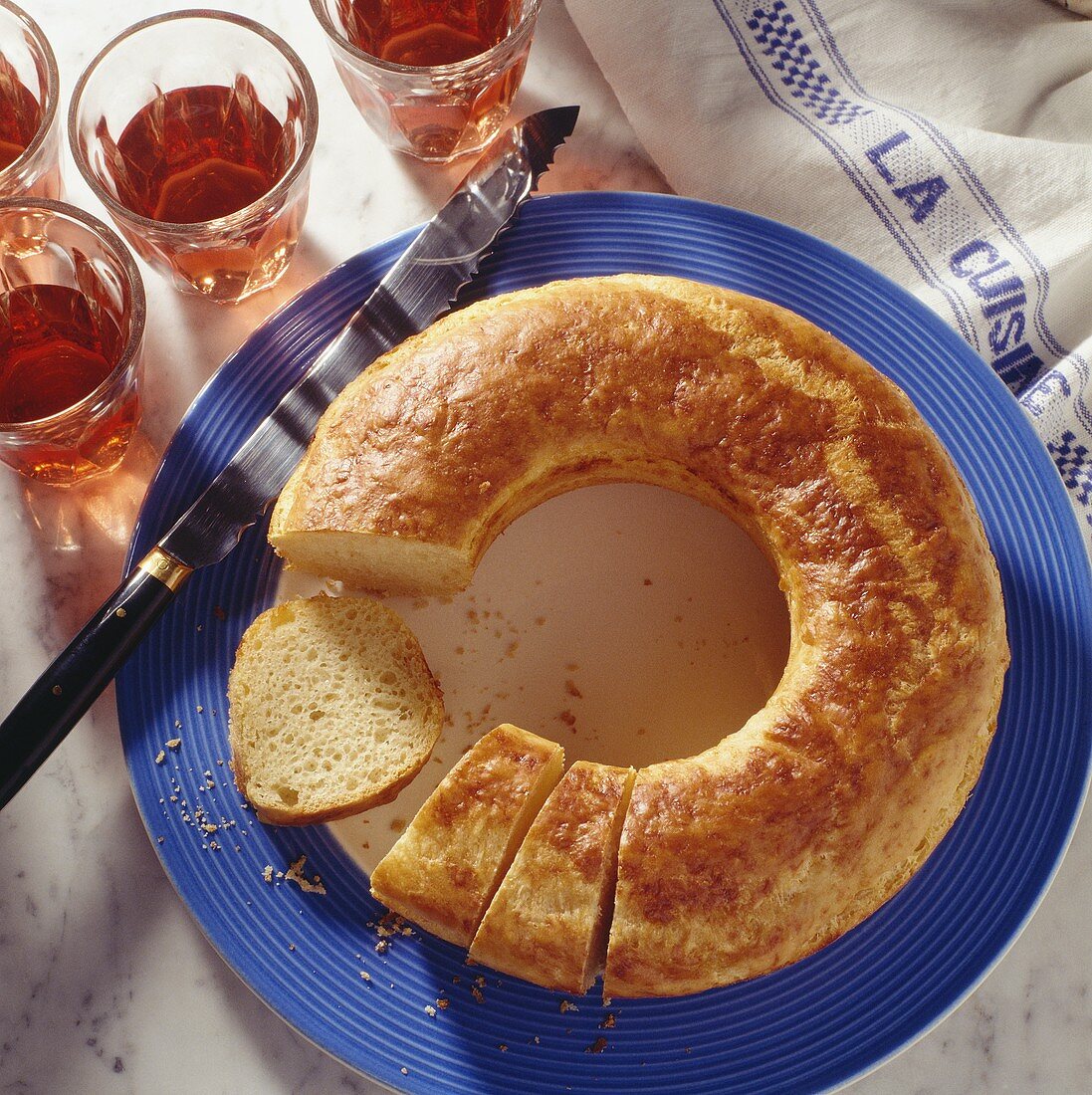 Baked Cheese Brioche in Ring Form, partially sliced, on blue Plate