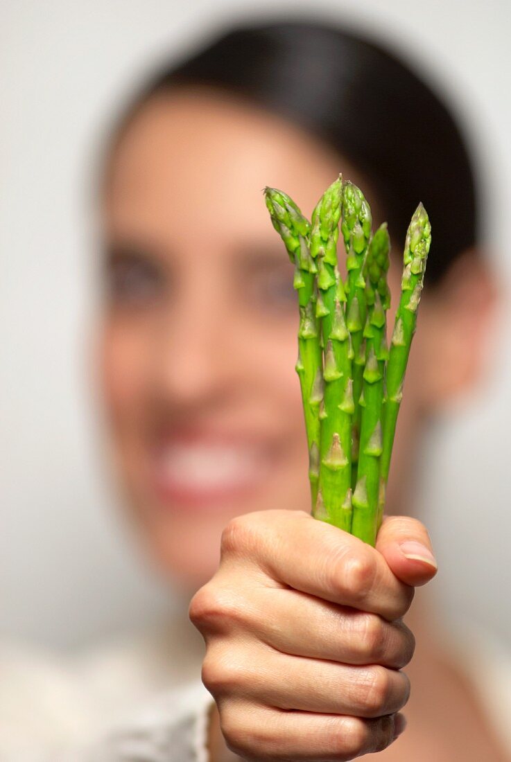 A woman holding green asparagus