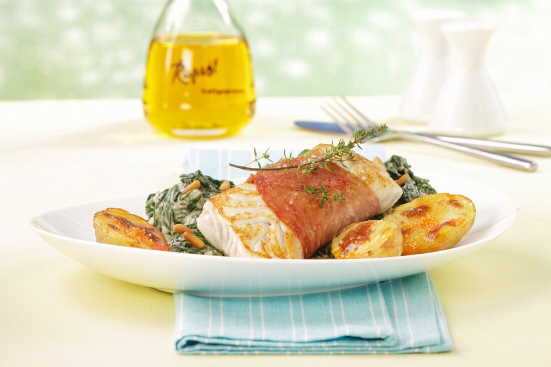 Salmon fillet wrapped in bacon with spinach and potatoes