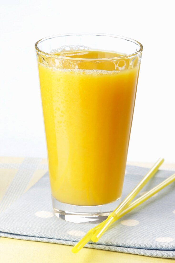 A glass of orange juice and a straw