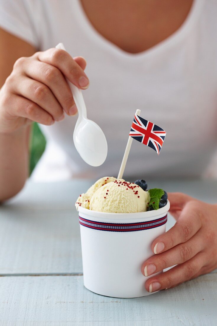 Vanilleeis mit frischen Blaubeeren und britischer Flagge in einem Becher