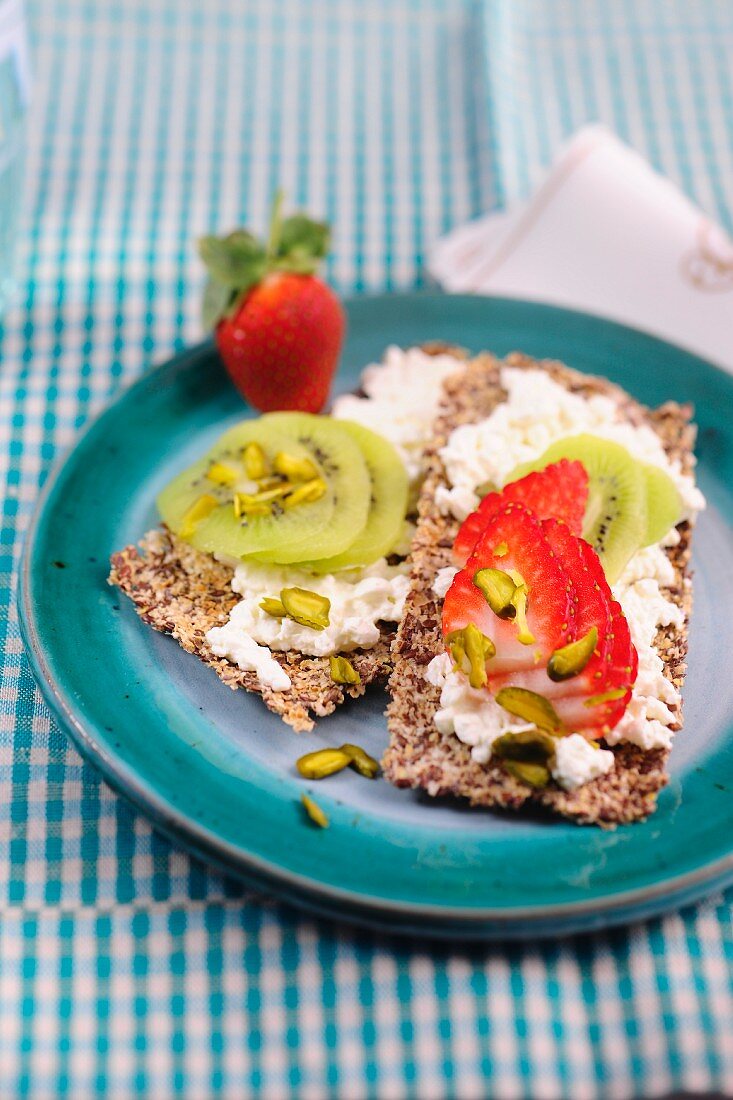 Crispbreads topped with cottage cheese, strawberries, kiwis and pistachios