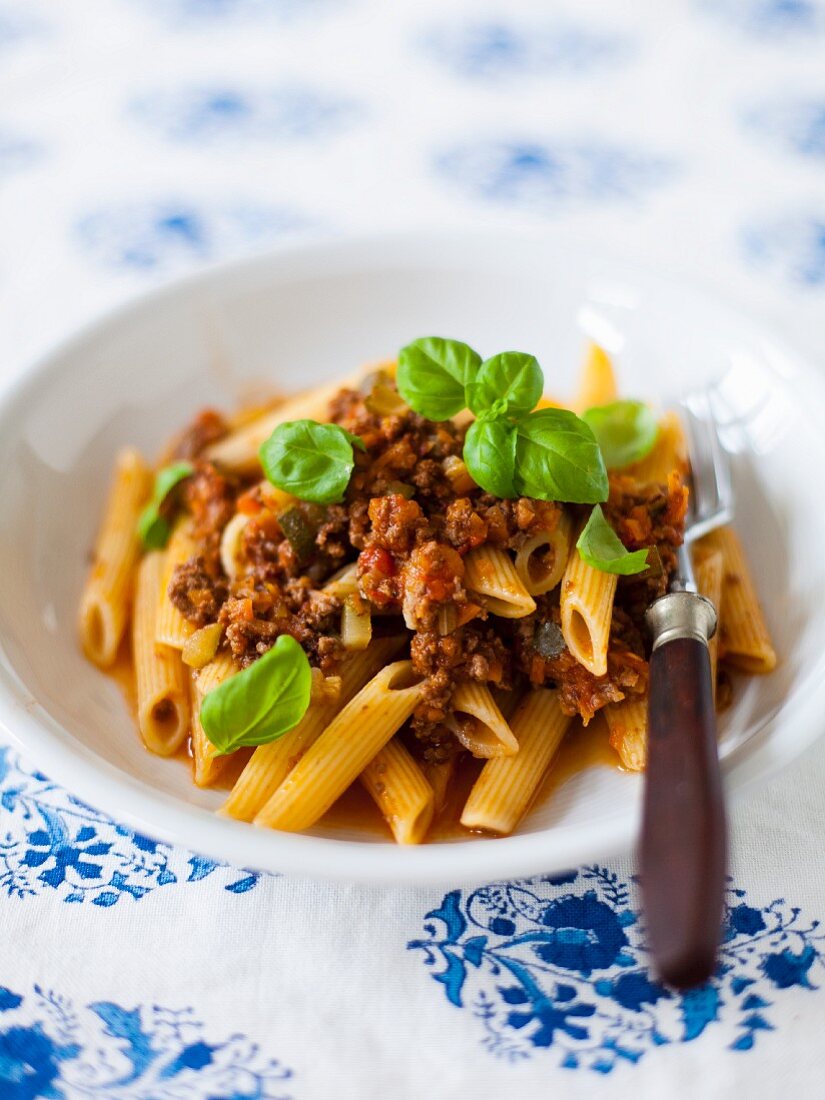 Penne pasta with a minced meat sauce and basil