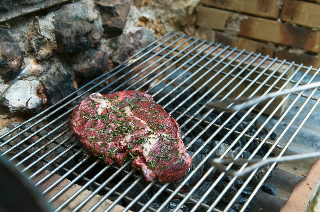 A beef steak with herbs on a barbecue