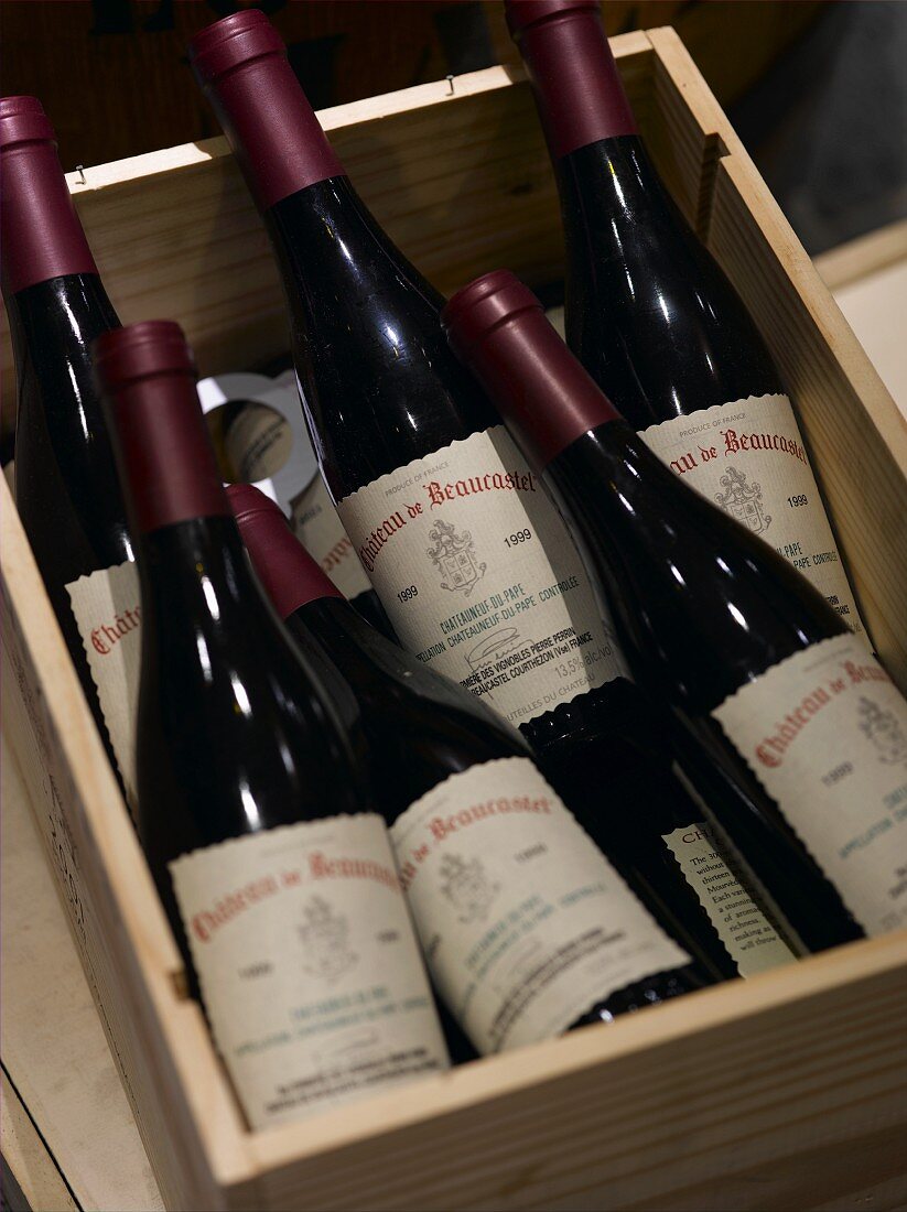 Stickered red wine bottles in a wooden crate