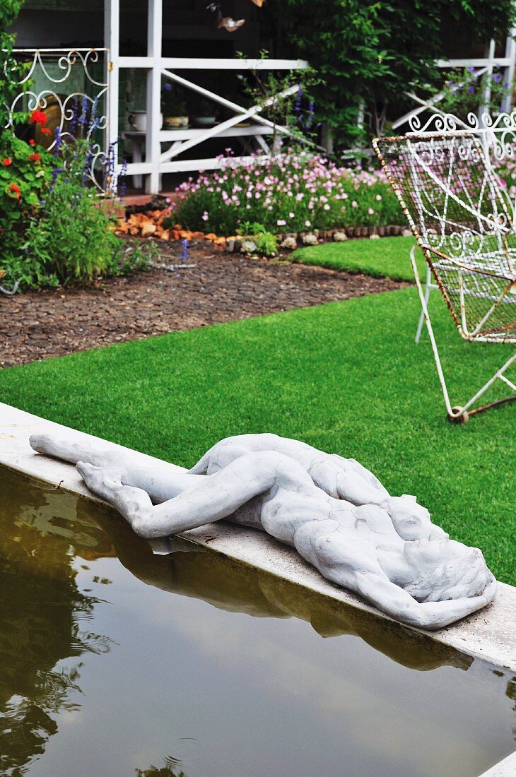 Pond with concrete surround and statue in tidy garden