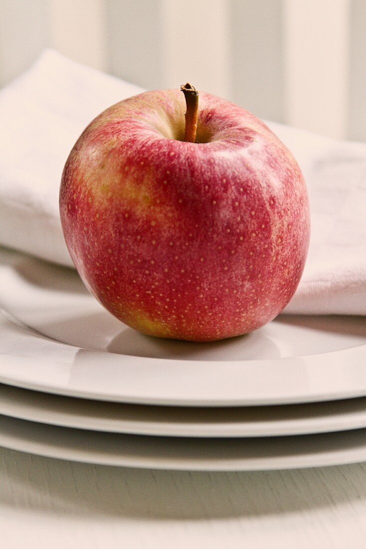 An apple on a stack of white plates