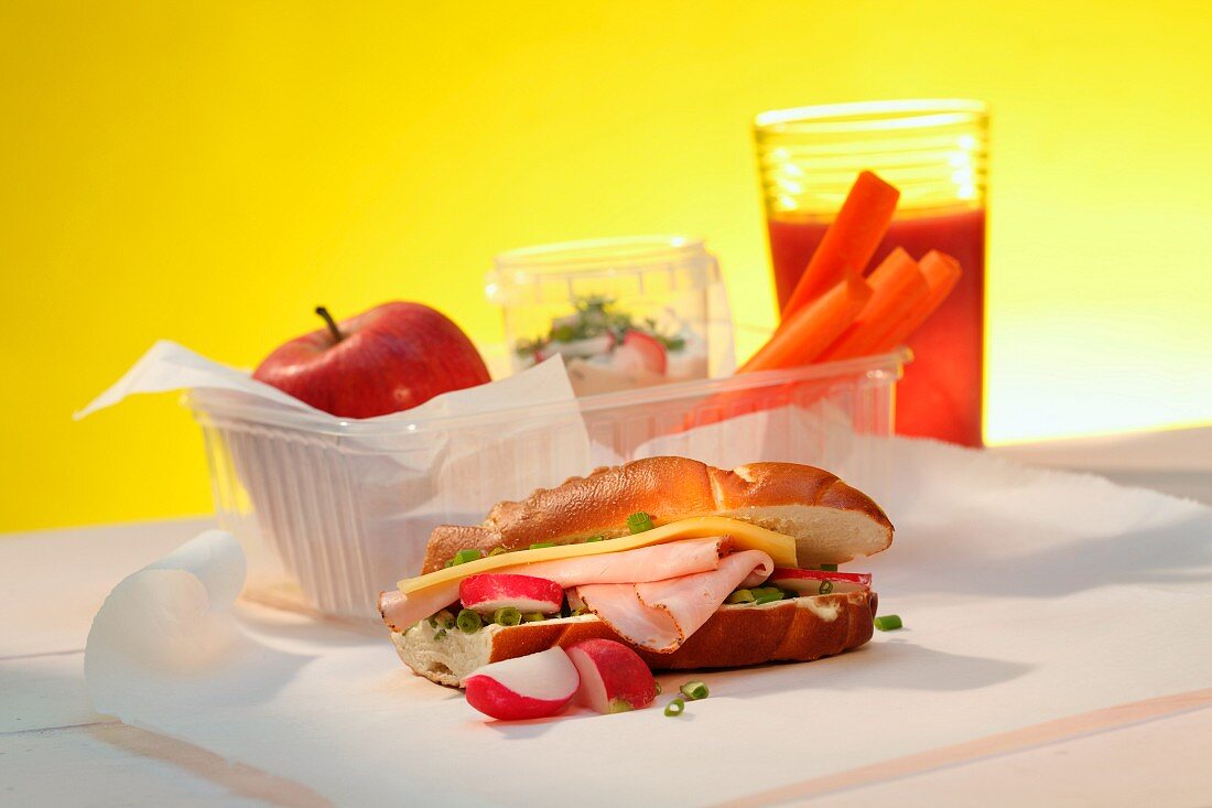 A sandwich, an apple, carrots and a raspberry smoothie with a lunchbox