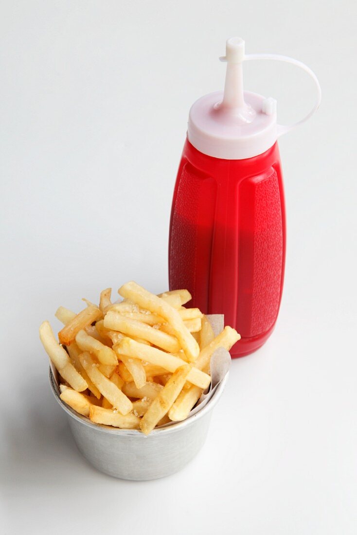 A bowl of chips and a bottle of ketchup