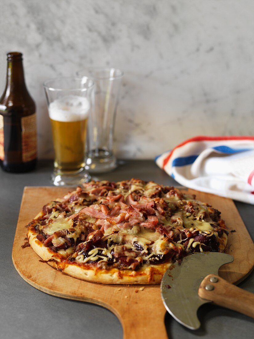 Pizza mit Schinken, Hackfleisch und Käse, Bier