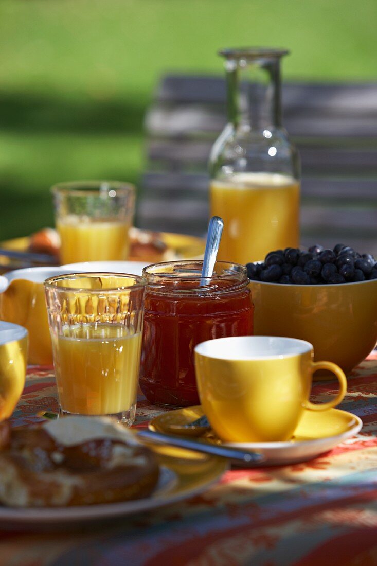 Sommerliches Frühstück im Garten mit Orangensaft und Marmelade