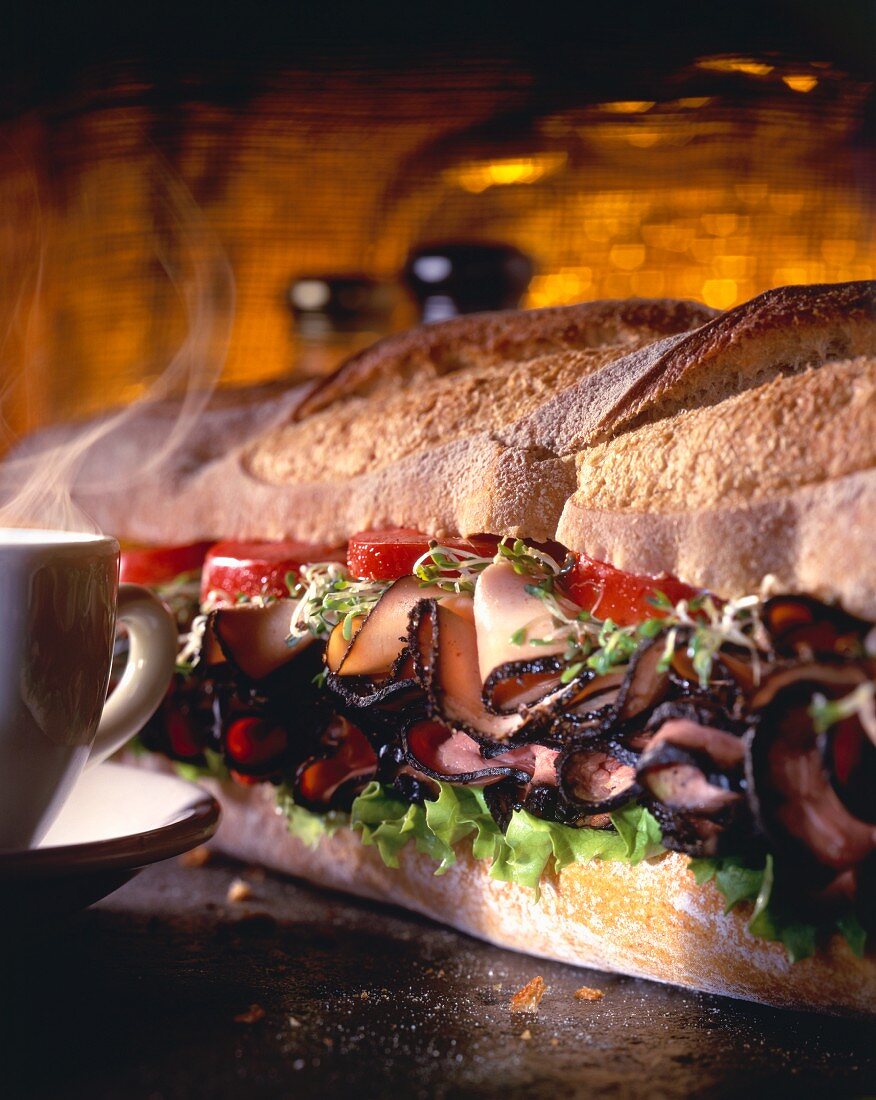 A Large Sub Sandwich with a Steaming Cup