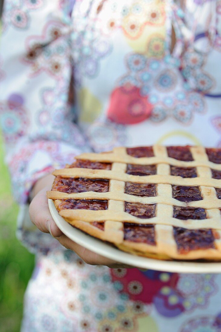 Frau hält eine Tarte du Champsaur (Obsttarte, Frankreich)