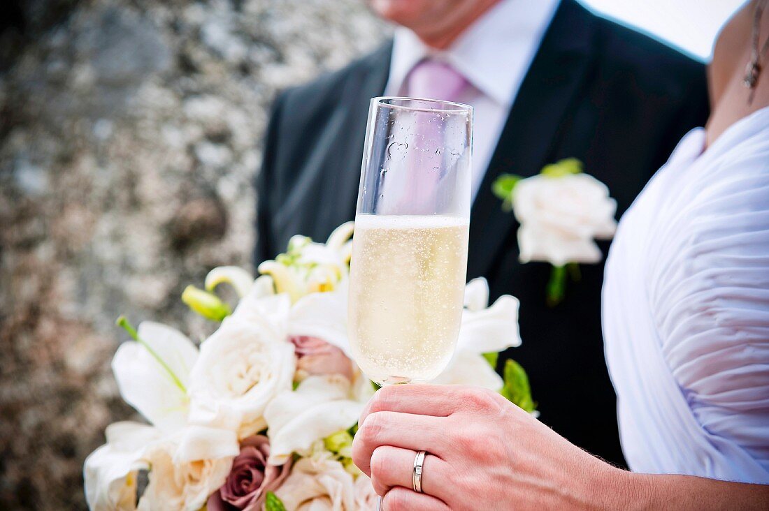 A bride and groom with a glass of champagne and a bouquet