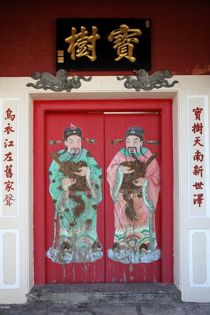 Red front door painted with figures of two men and Chinese characters