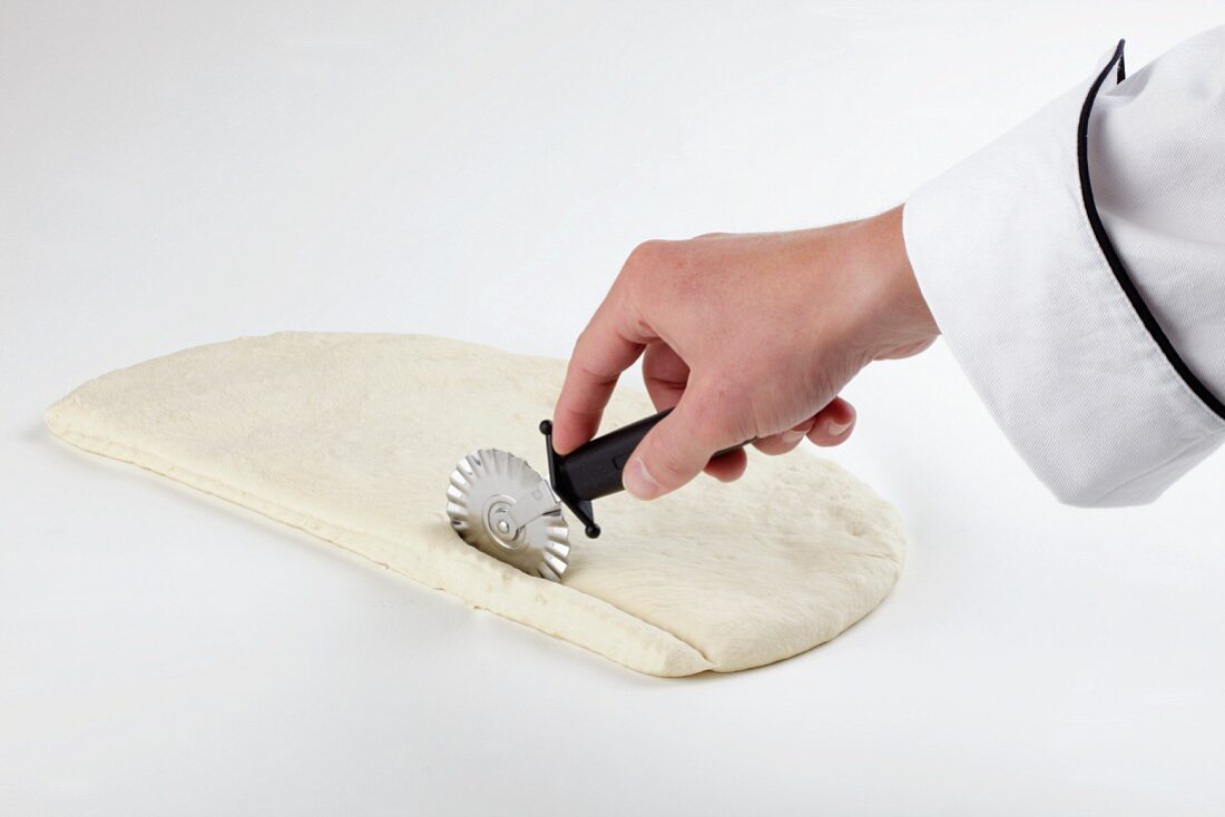 Pizza dough being cut