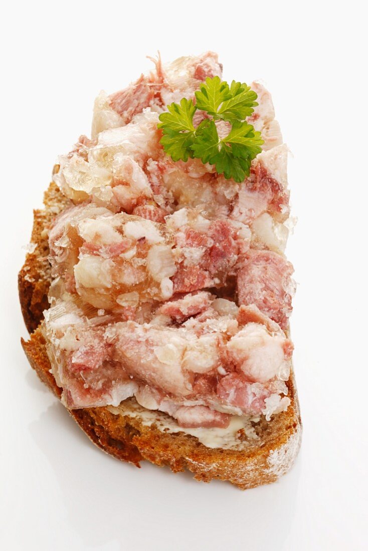 A slice of bread topped with pork head in aspic