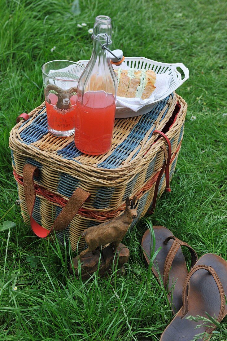 A picnic basket with sparkling juice and sandwiches