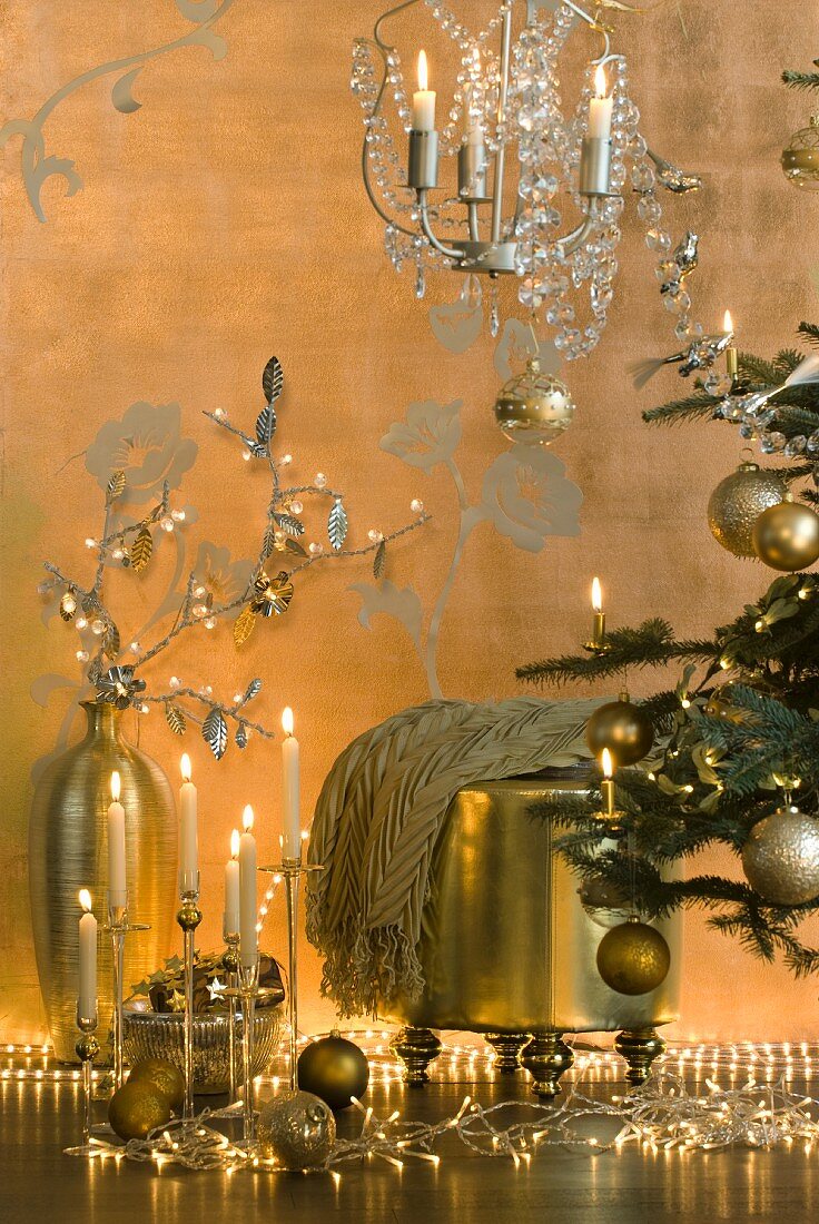 Weihnachtsdekoration in Gold neben dem Tannenbaum - Lichterkette, Kerzendeko, Bodenvase und Hocker