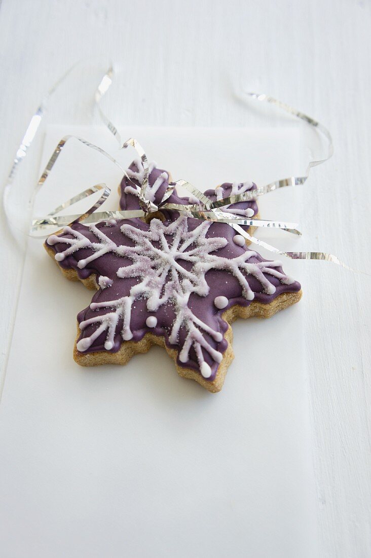 A snowflake biscuits decorated with purple icing sugar