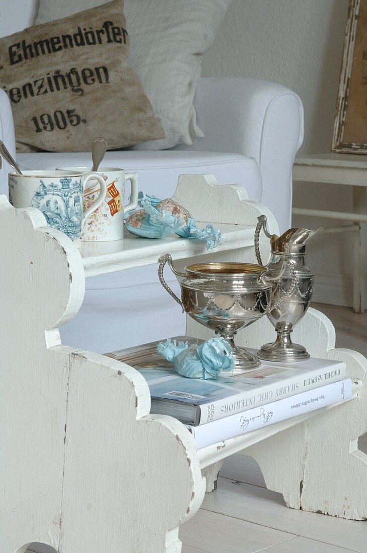 Silver goblets and cups on white wooden stepladder