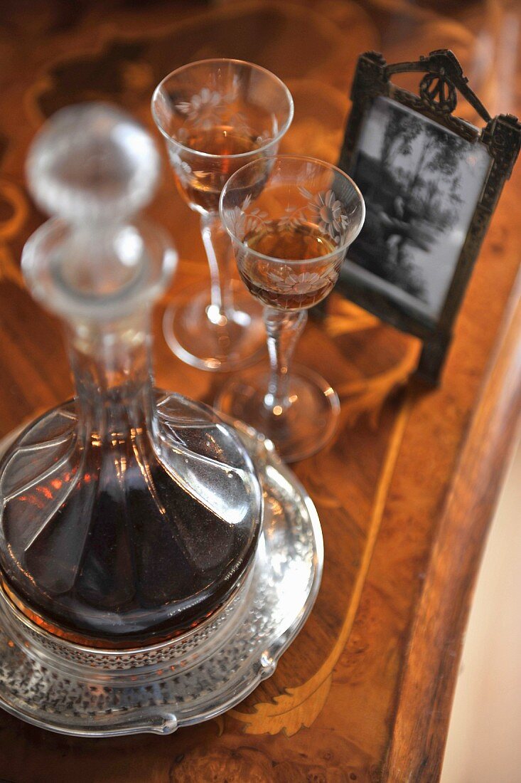 Glass decanter and liqueur glasses on antique wooden table