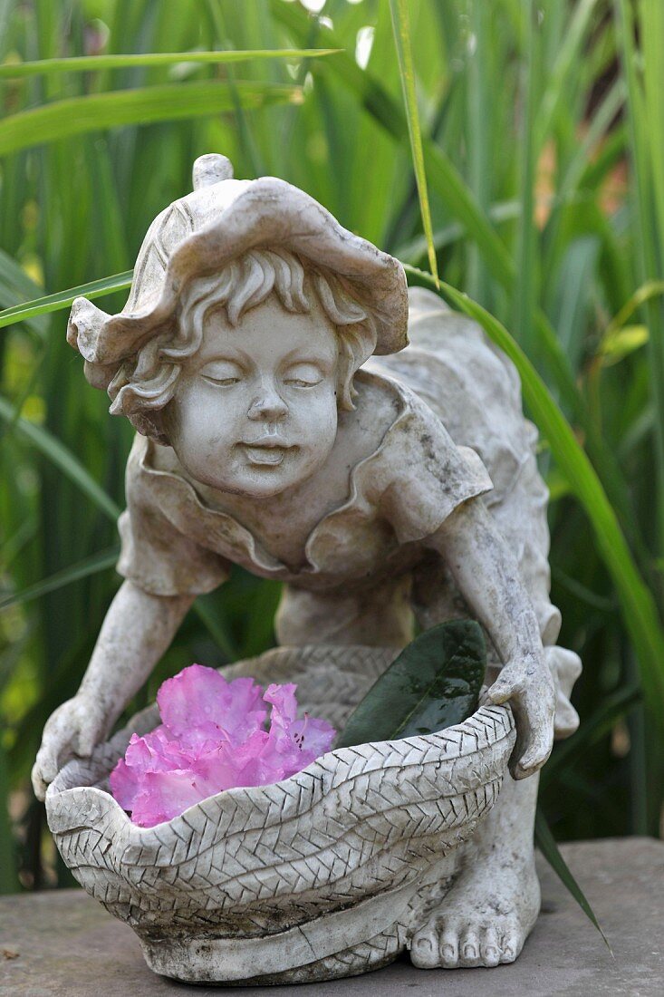 Stone figurine of child decorated with flowers