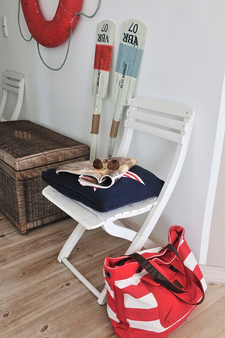 Boat house - fabric bag next to chair and paddles and lifebelt on wall