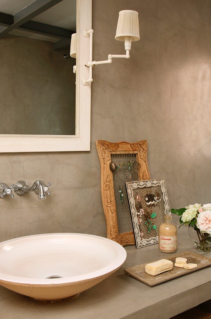 Vintage wooden frame next to washbasin on concrete surface below wall mirror