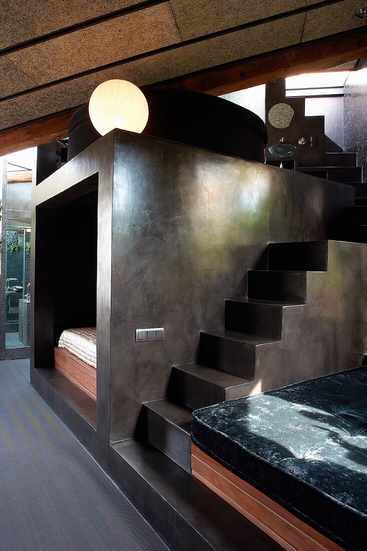 Stairs next to installation with grey, trowelled paint effect in open-plan interior