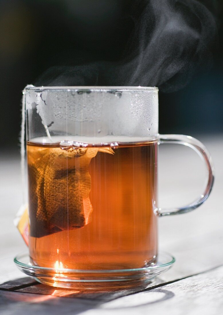 Dampfender Tee im Glas mit Teebeutel