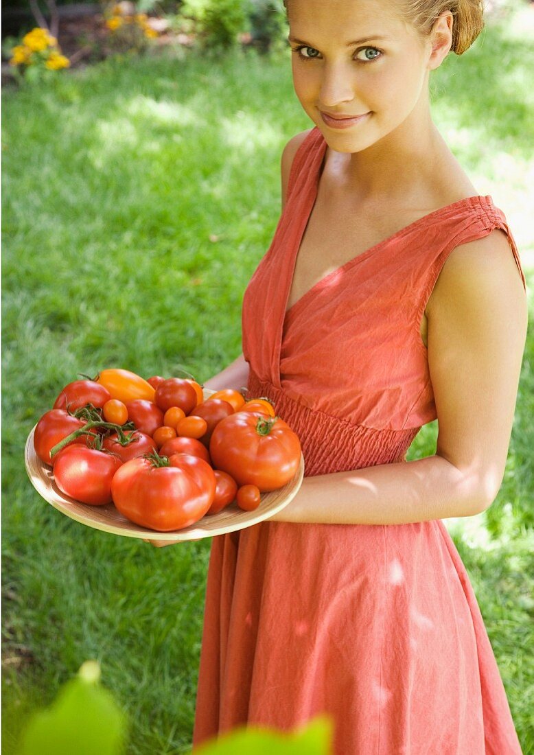Junge Frau hält einen Teller Tomaten