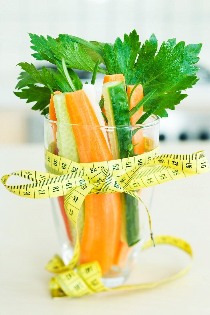 Measuring tape tied in a bow around a glass filled with fresh vegetables