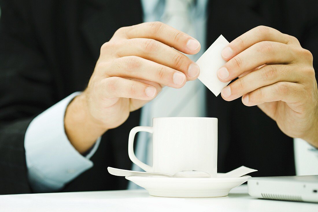 Geschäftsmann öffnet Zuckertüte für den Kaffee
