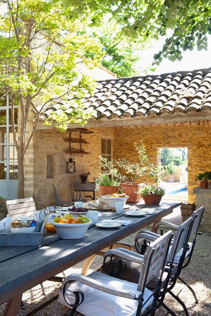Long breakfast table in sunny courtyard of Mediterranean country house