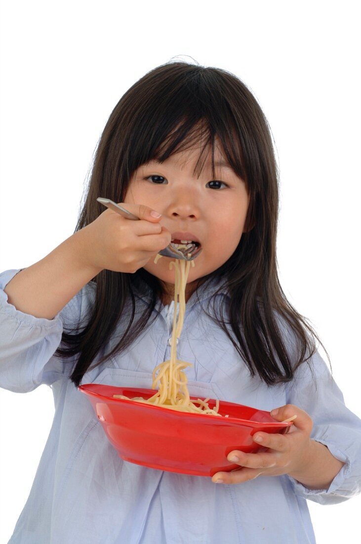 Girl eating spaghetti from bowl