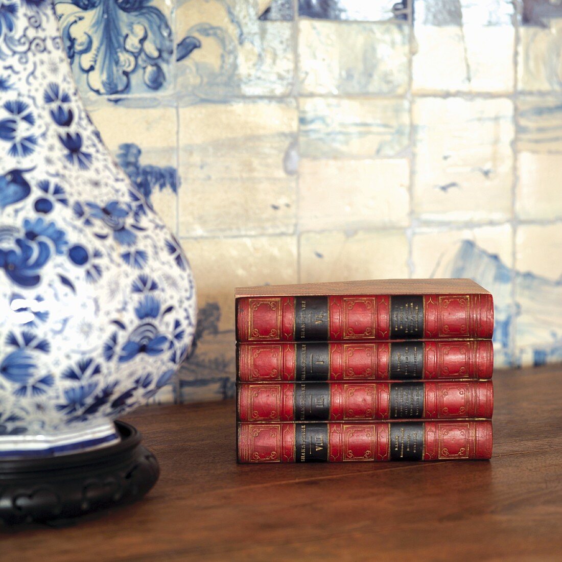 Antique books on table next to table lamp with white and blue ceramic base