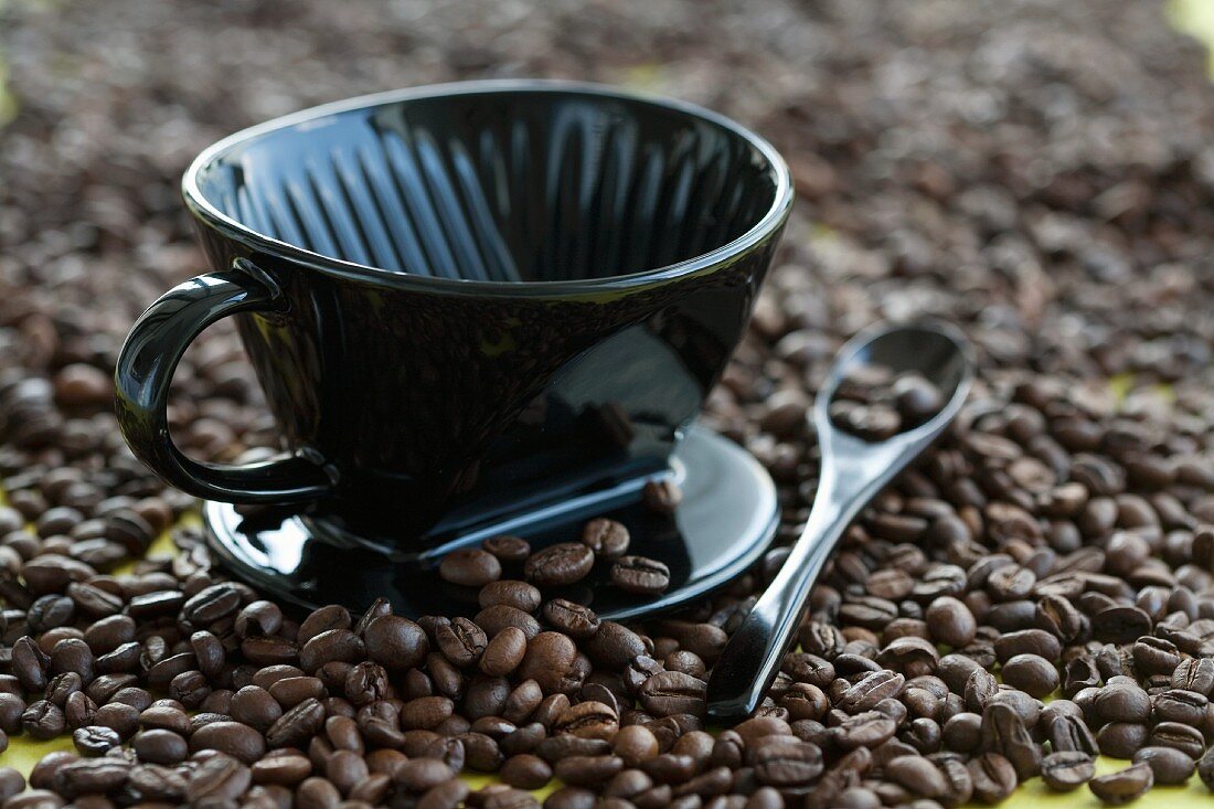 Schwarze Kaffeetasse und Löffel auf Kaffeebohenn