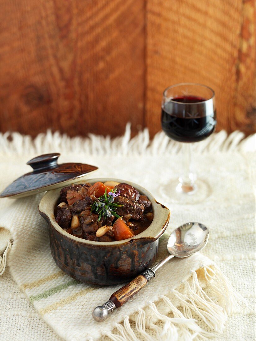 Rindfleischeintopf mit Karotten, dazu Rotwein im Glas